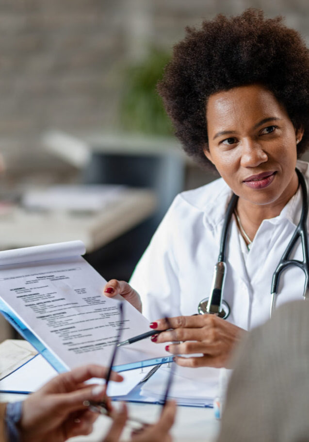 African American female doctor showing to a couple test results of their medical exam at clinic.